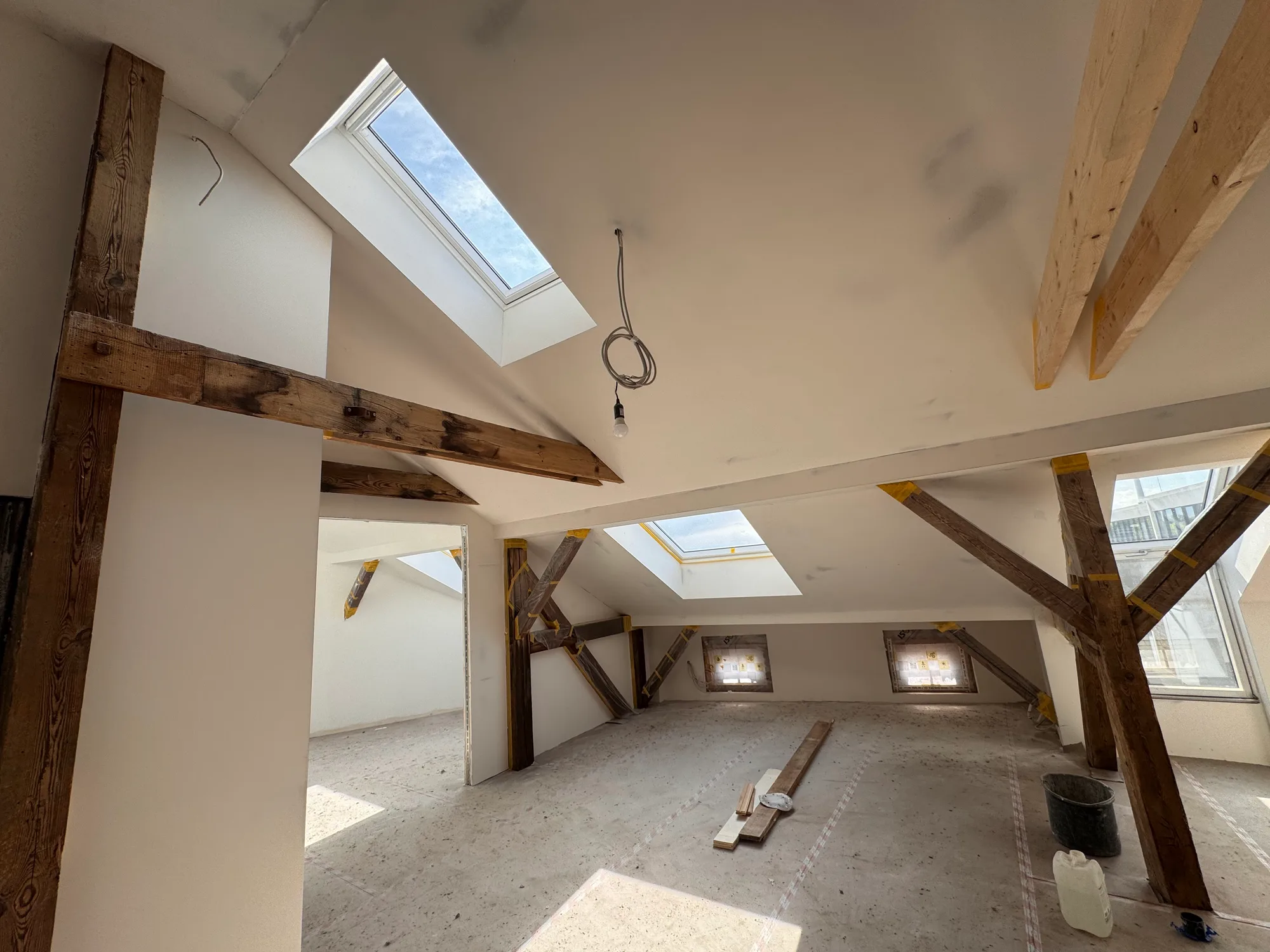 Dachausbau Referenz – ausgebautes Dachgeschoss mit freiliegenden Holzbalken und Dachfenstern in Berlin